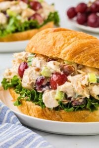sideways shot of filled croissant sandwich on counter with grapes in background.