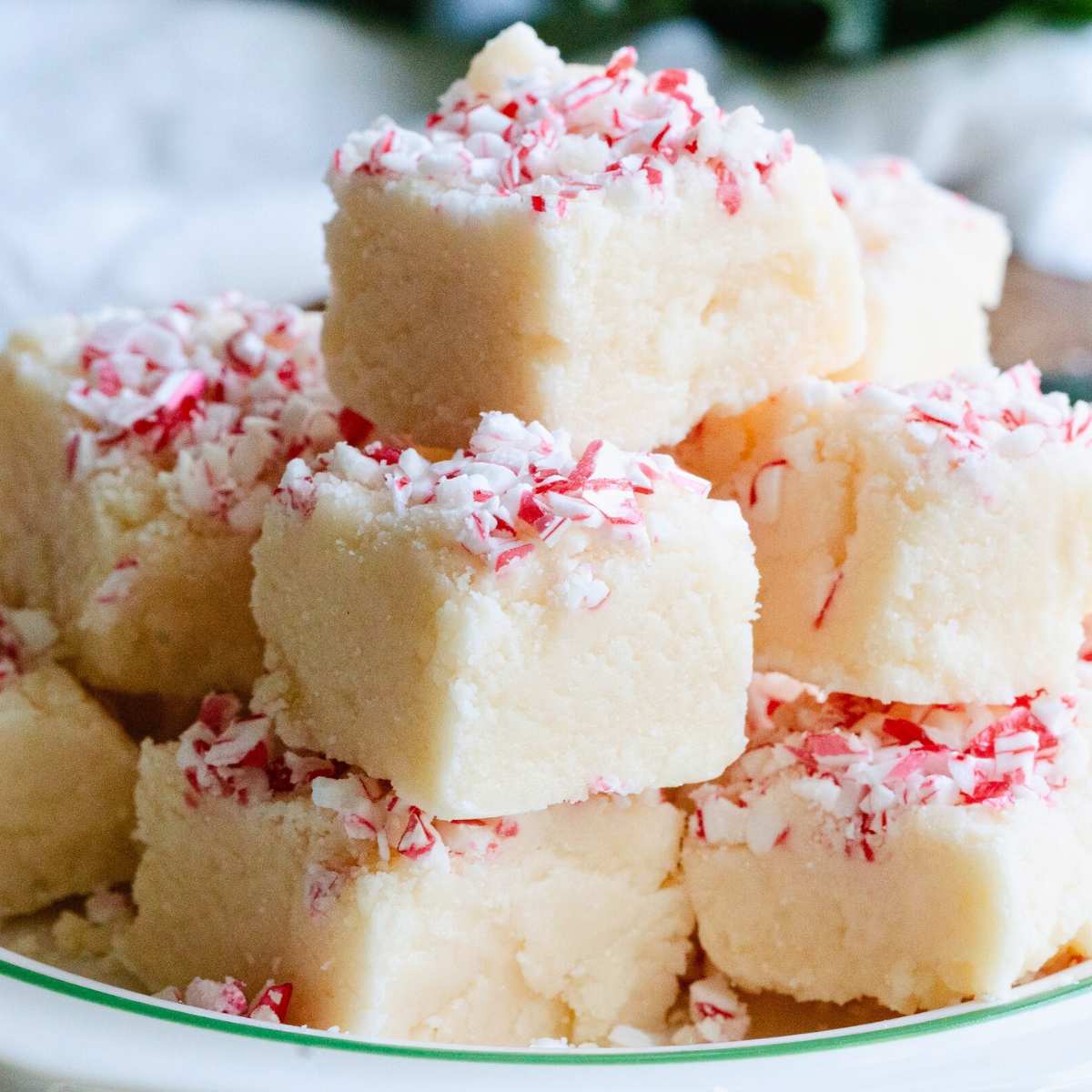 close up of peppermint fudge pieces stack on plate.