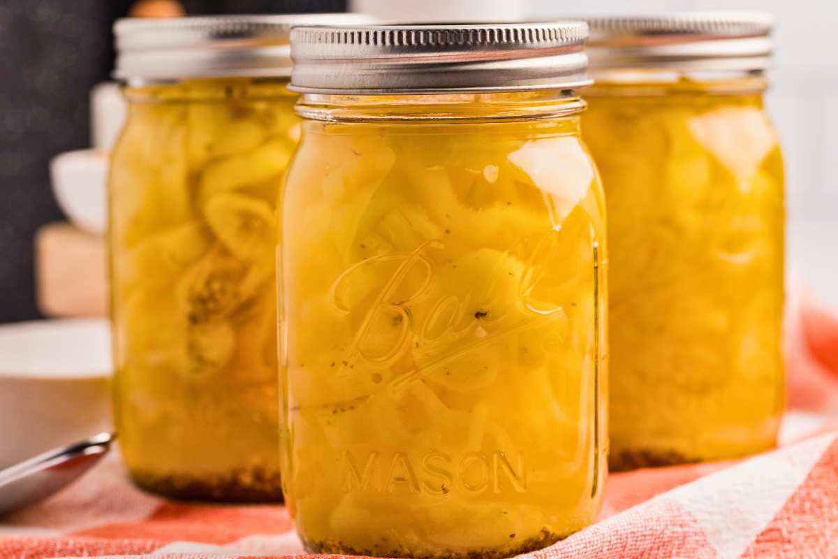 front close up shot of 3 jars of pickled banana peppers.
