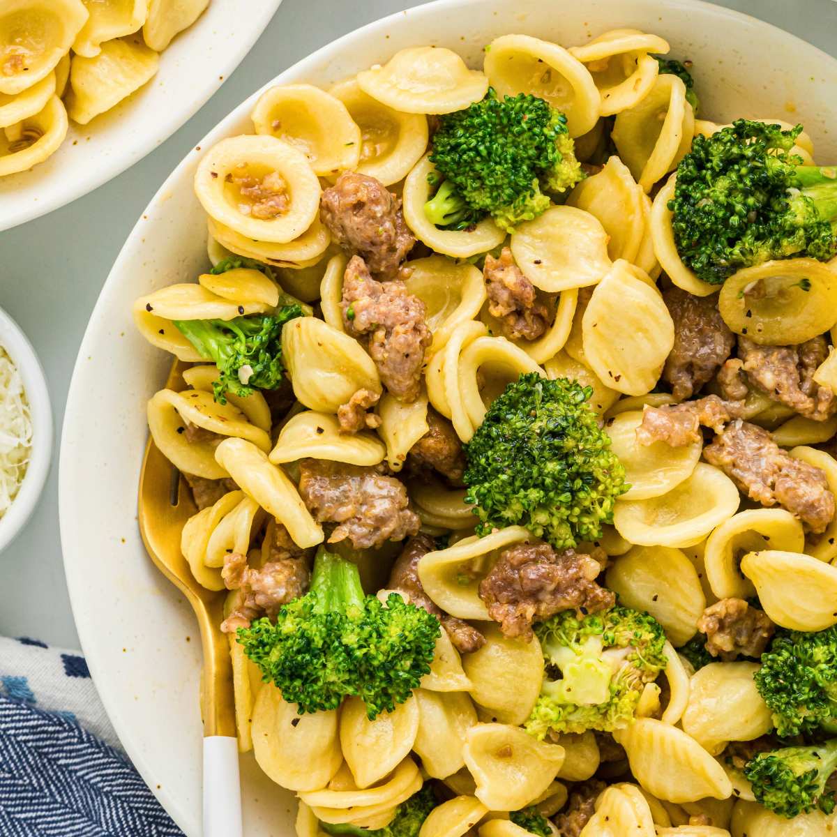 pasta dish with broccoli and sausage on white plate with fork.