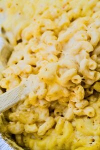 close up of mac and cheese with wooden spoon stirring.