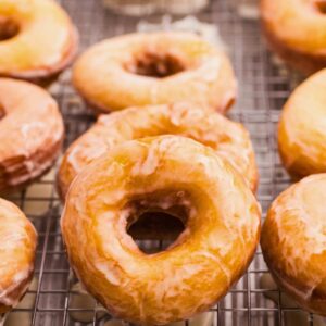 sourdough doughnuts with glaze on cooling rack.