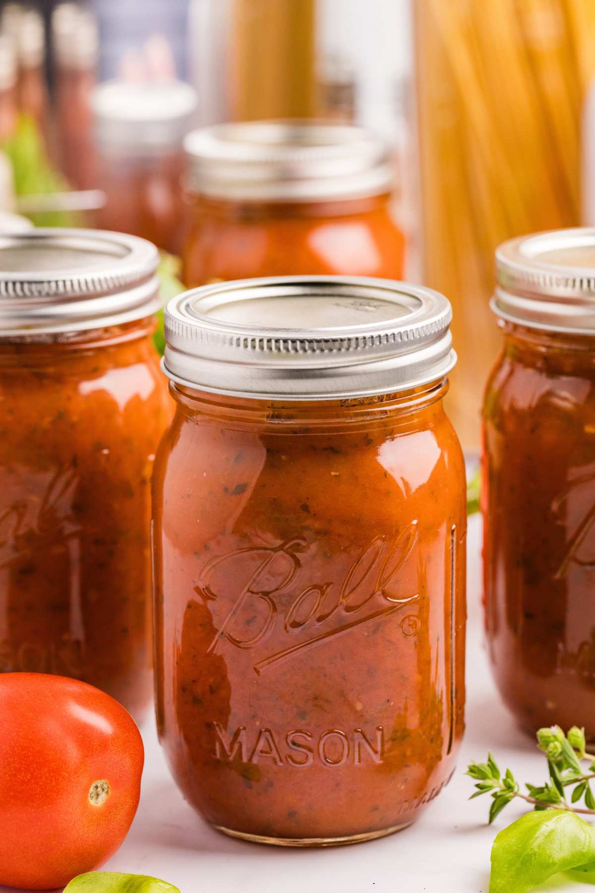 canned jars of spaghetti sauce on counter with tomato on side.