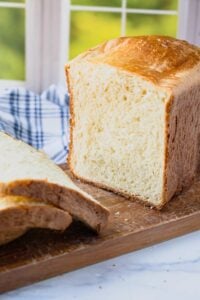 brioche loaf with two slices cut on wooden board.