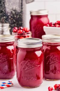 jars of cranberry juice arranged on counter with bowls of cranberries.