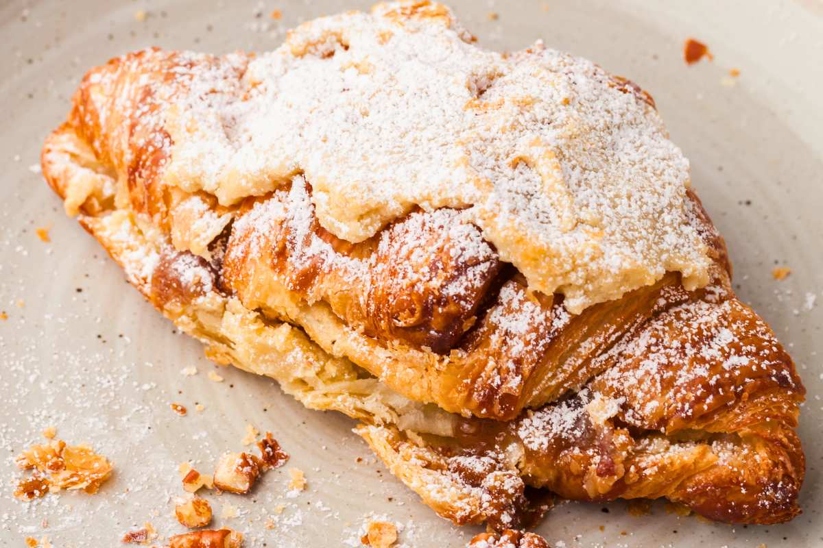 close up of one sugar dusted pecan pie croissant on plate.