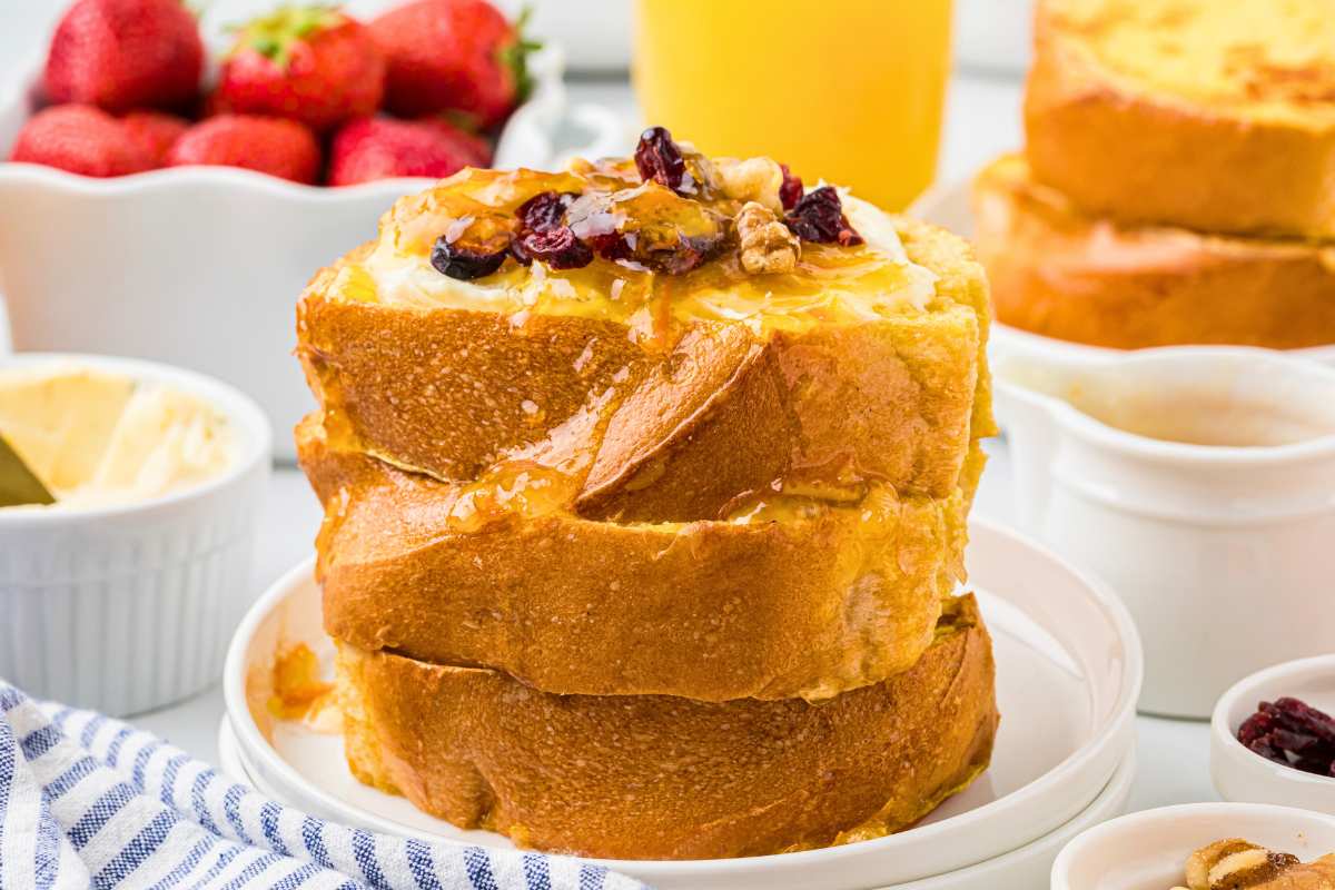 stacked French toast with cream cheese, orange sauce, walnuts, and cranberries on top.