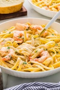 bowl of creamy shrimp alfredo pasta with fork twirled around noodles.