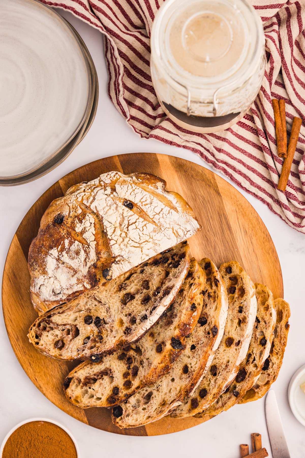 top view of cinnamon raisin boule bread with half of it sliced up on wooden board.