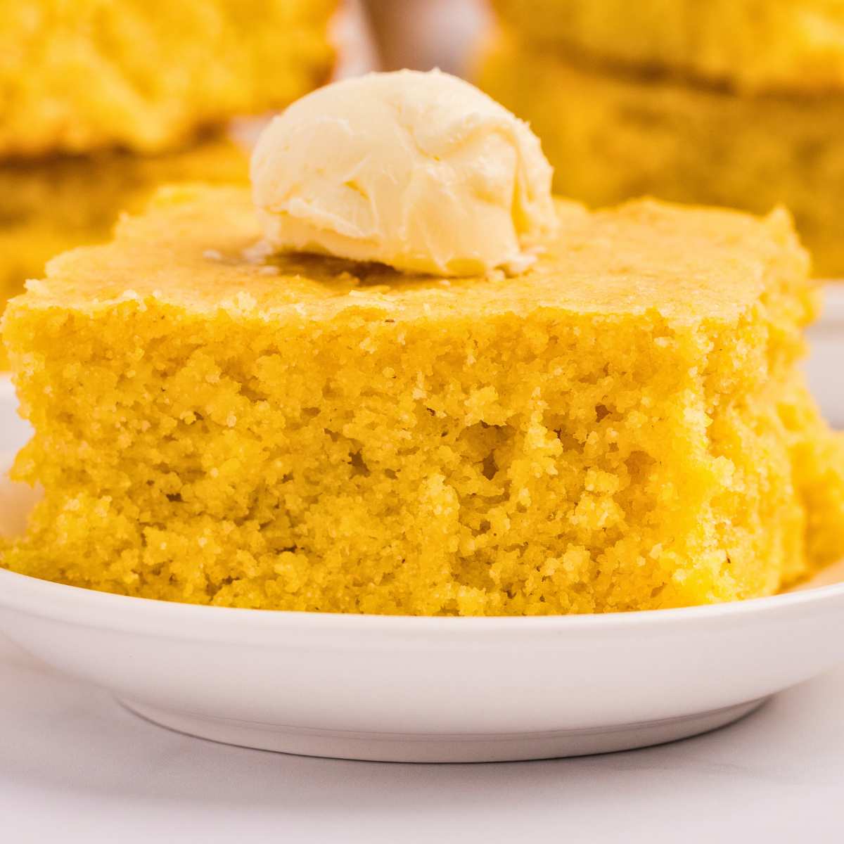 piece of cornbread on plate with butter on top.