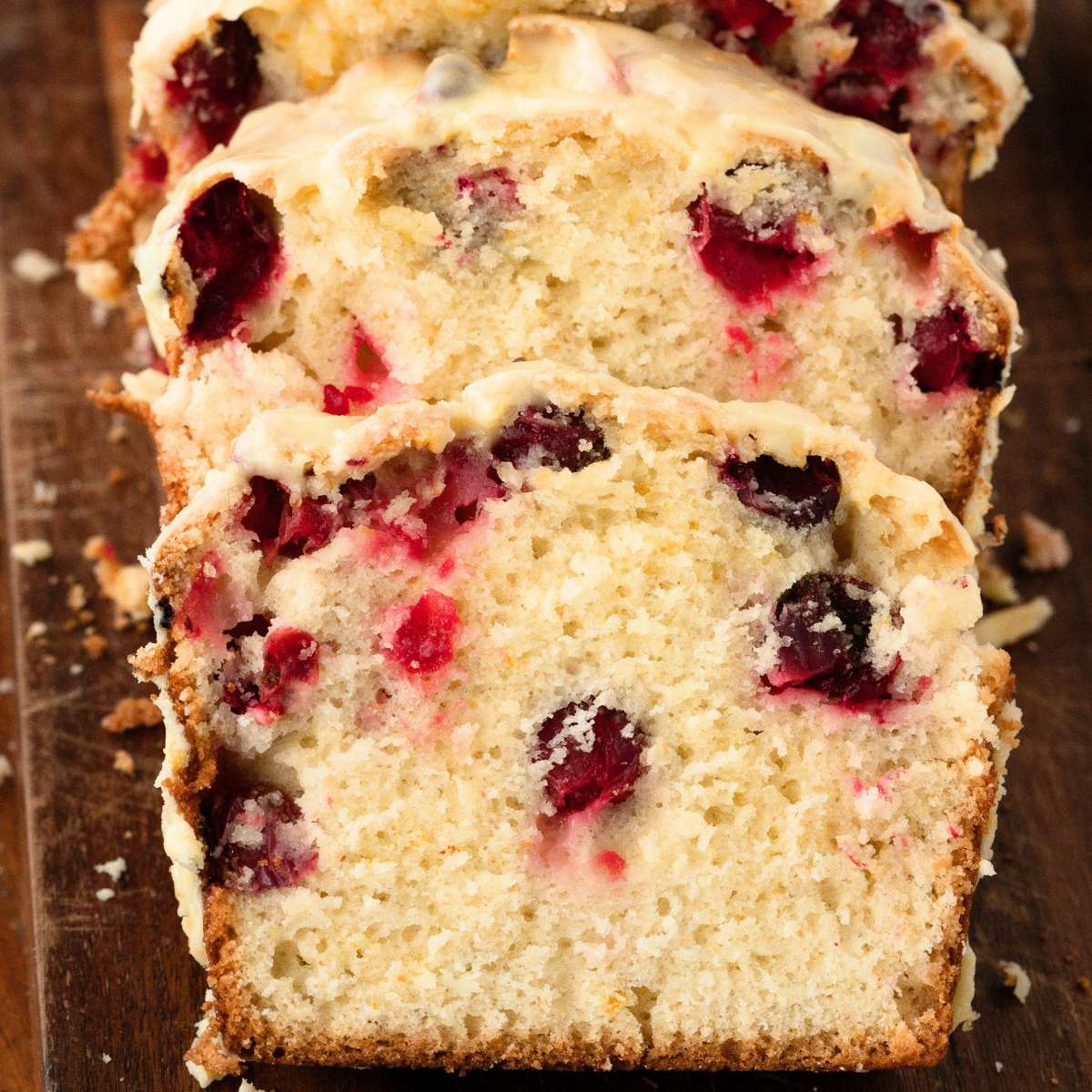 loaf of cranberry quick bread sliced on board.