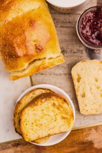 overhead shot of bread loaf with two slices buttered on plate.