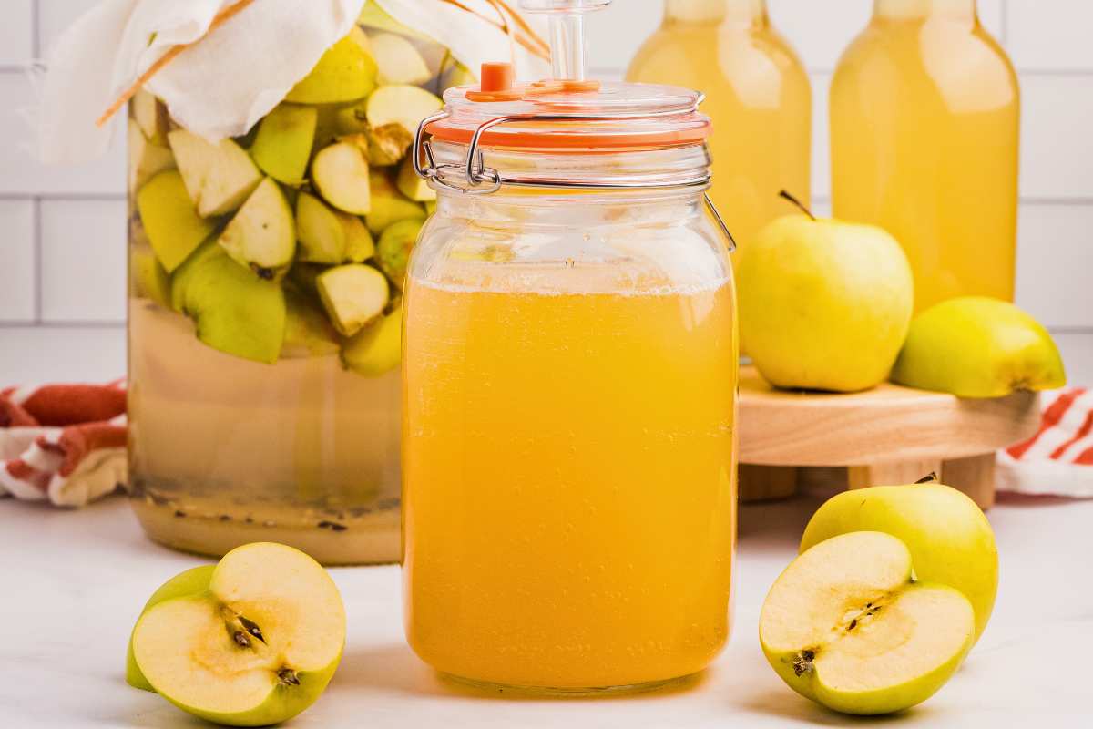 gallon jar of vinegar with apples around it.