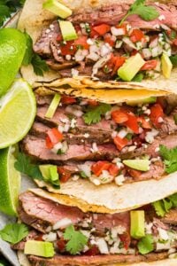 three flank steak tacos lined up vertically.