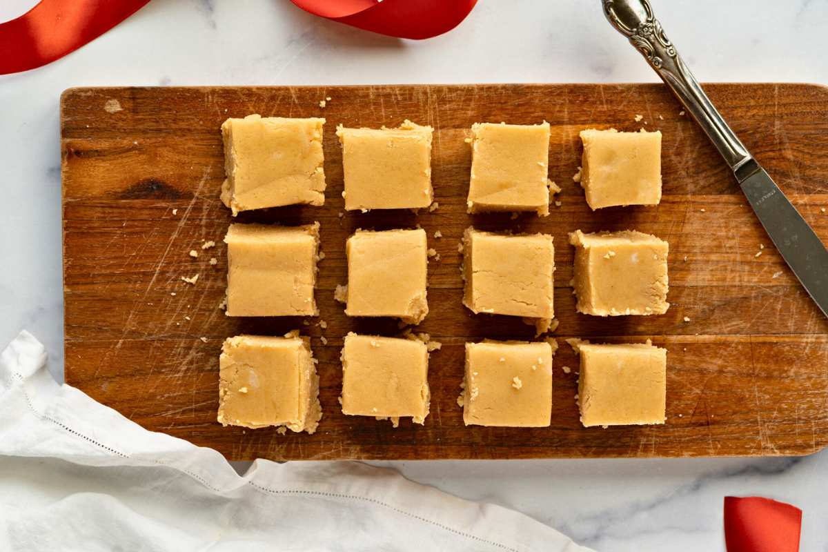 squares of peanut butter fudge on wooden cutting board.