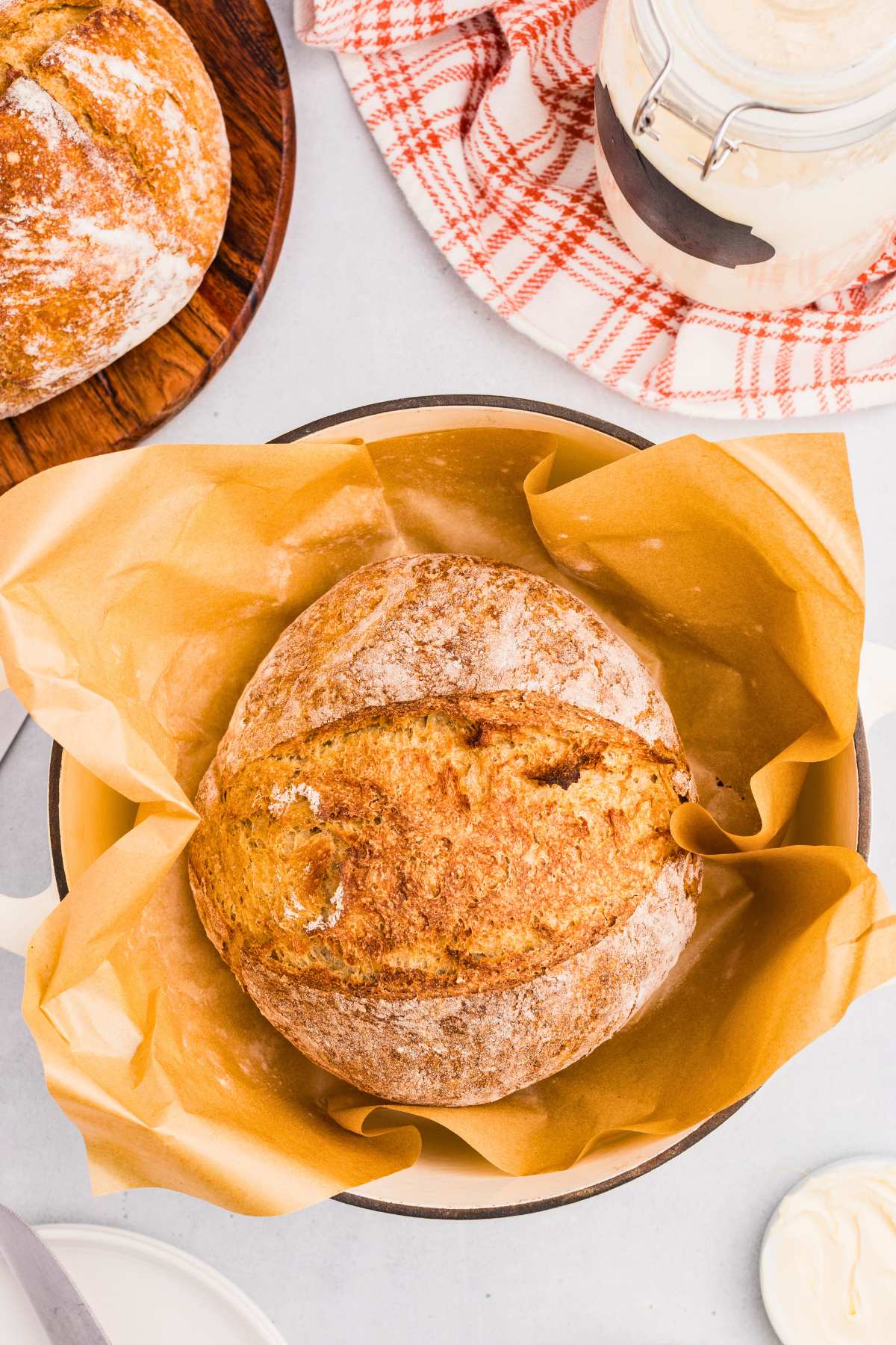 round spelt bread loaf in Dutch oven with parchment paper.