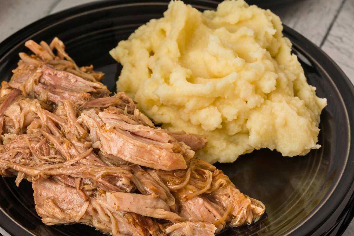 shredded pork roast with mashed potatoes on plate.