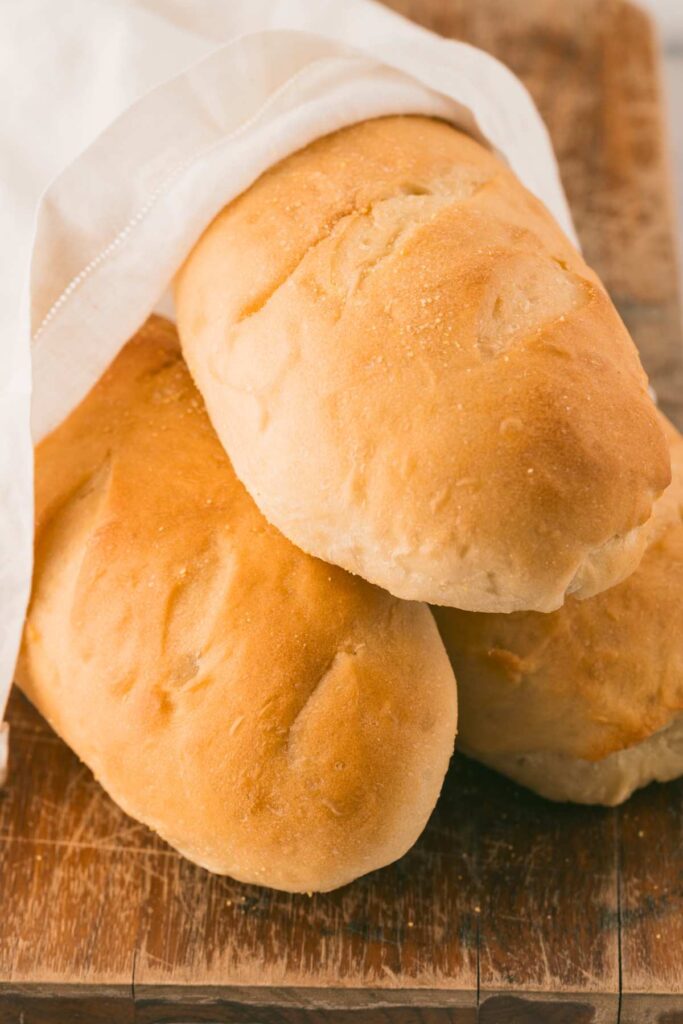 hoagie rolls in bread bag on wooden board.