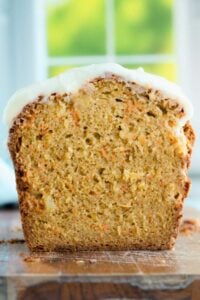 inside of carrot cake bread with icing on top on wooden board.