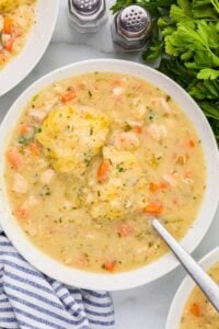 bowl of chicken soup with dumplings floating on top.