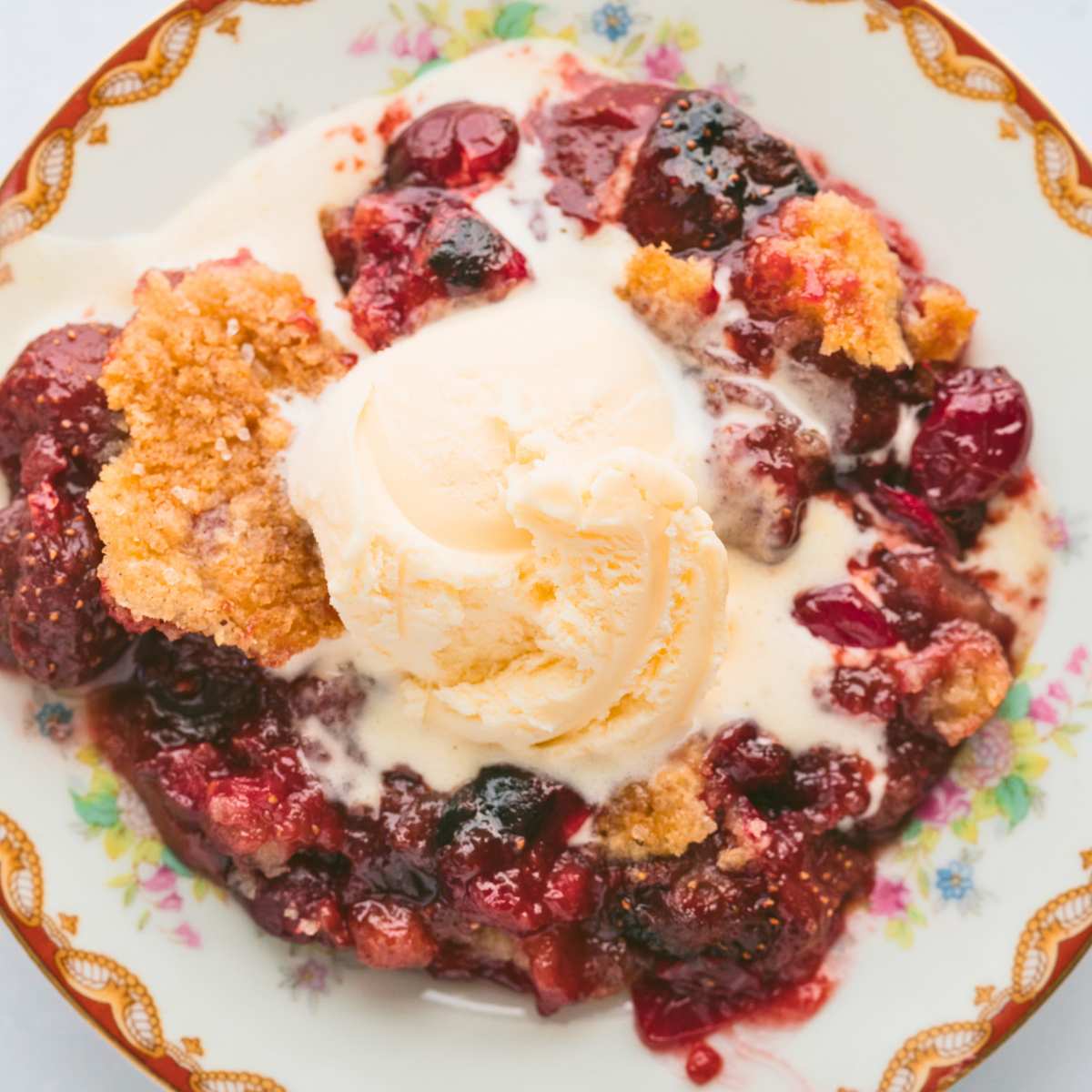 cobbler serving on plate topped with vanilla ice cream.