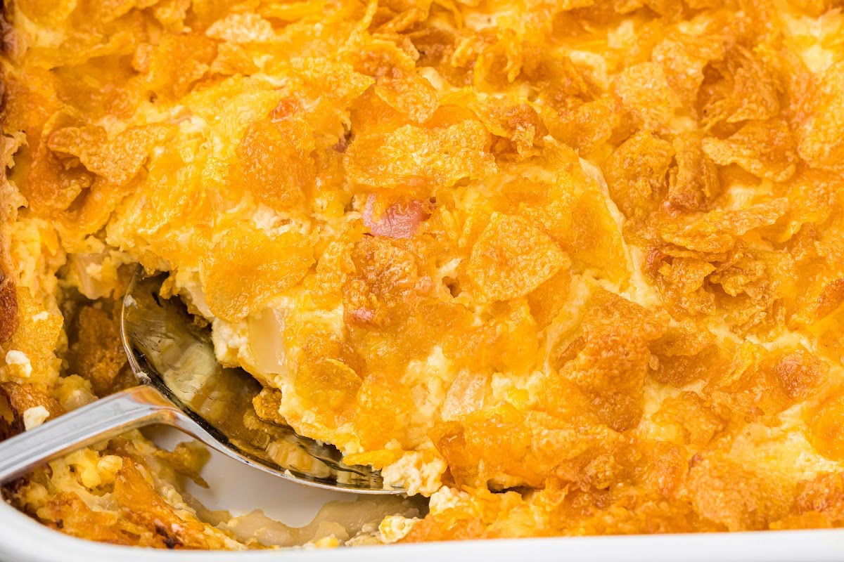 serving spoon lifting layer of casserole.