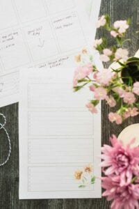peach planner pages on table next to pretty pink flowers.