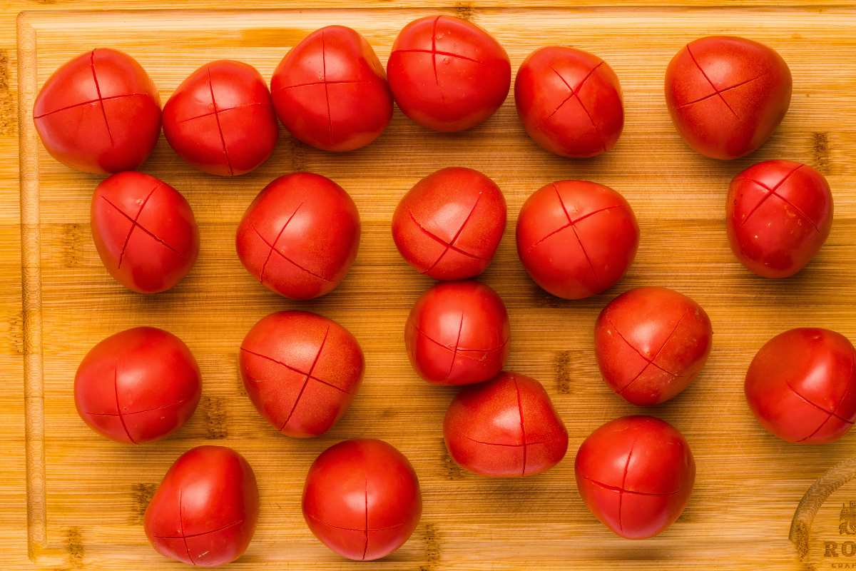 tomatoes on cutting board with X's scored on them.