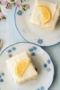 slices of lemon cake with lemon wedge on top on blue and white plates.