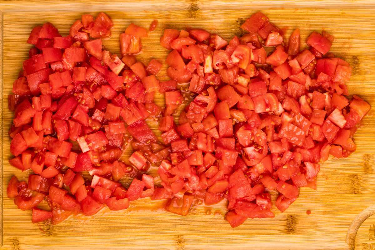 tomatoes diced up into small pieces on cutting board.