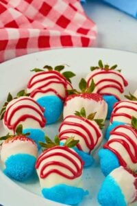 strawberries on white platter covered with blue and white icing with red icing drizzled on top.