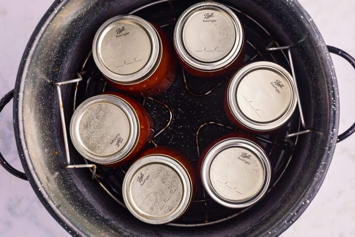 filled and sealed jars processing in canner.