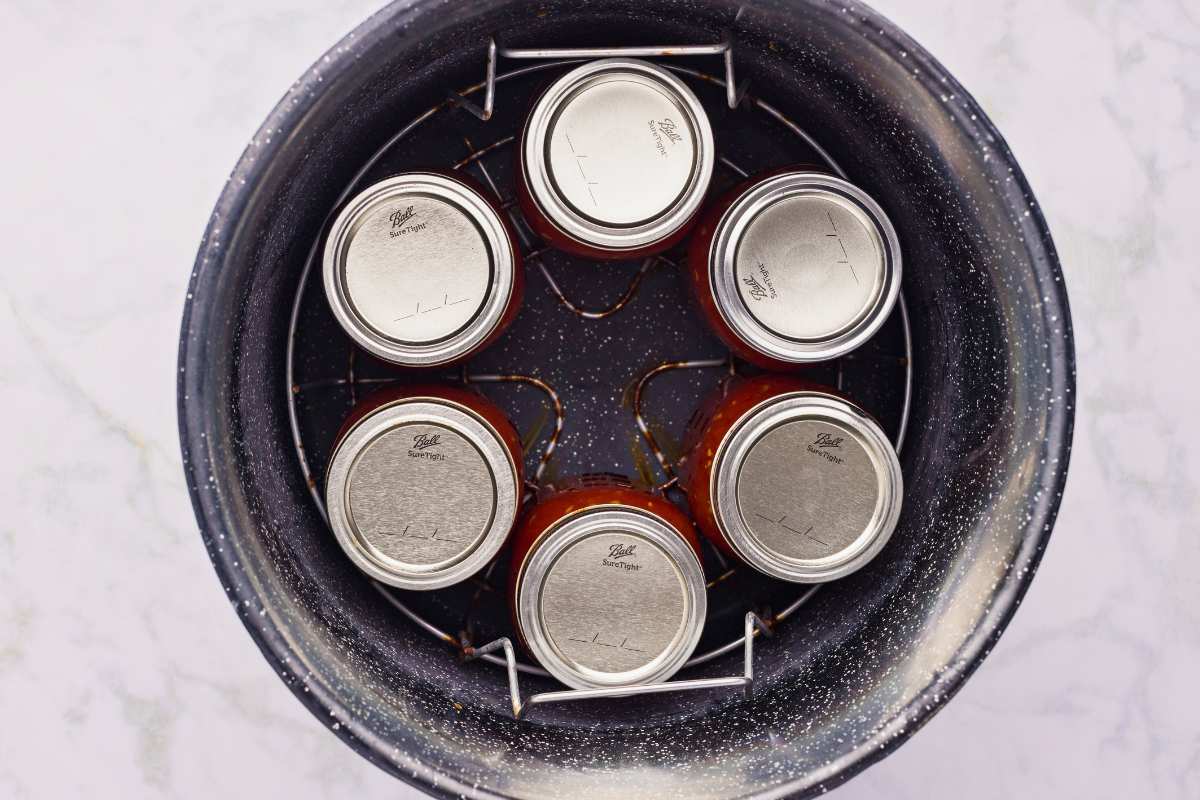 filled and sealed jars in canner for processing.