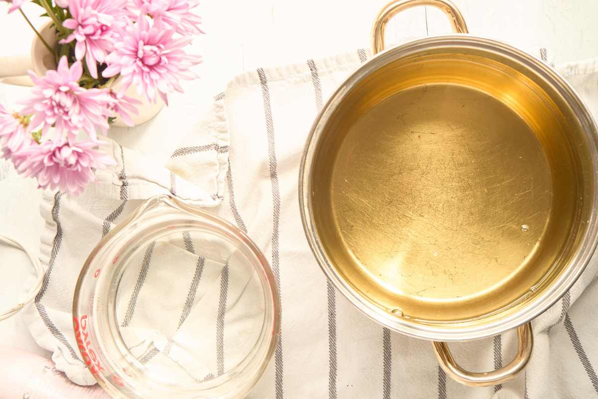 a large stainless steel pot with melted oils and an empty Pyrex measuring cup.