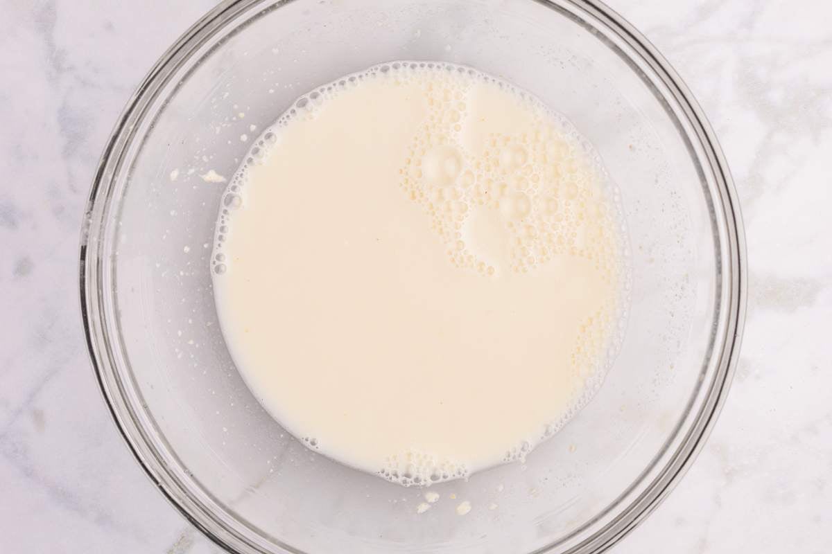 Sourdough starter and water mixed in a glass bowl.
