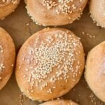 golden brown baked rolls topped with sesame seeds on baking sheet.