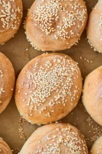golden brown baked rolls topped with sesame seeds on baking sheet.