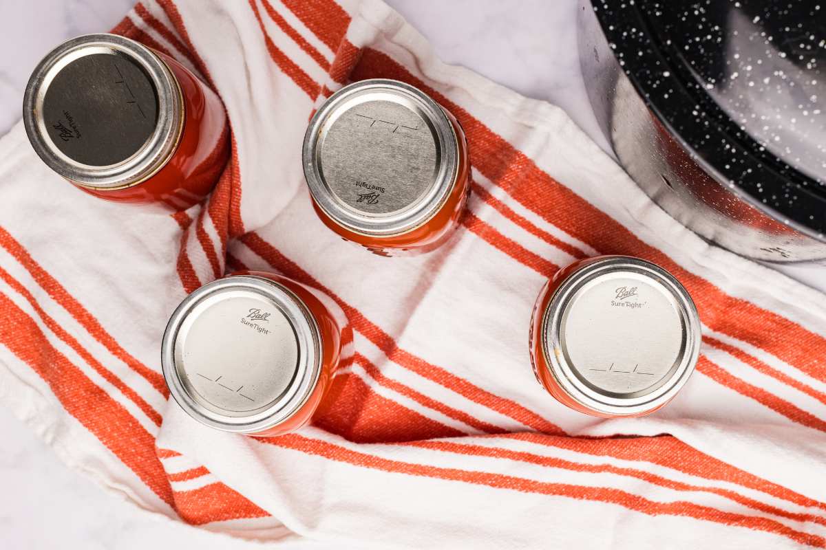 Four sealed jars cooling on a striped towel.
