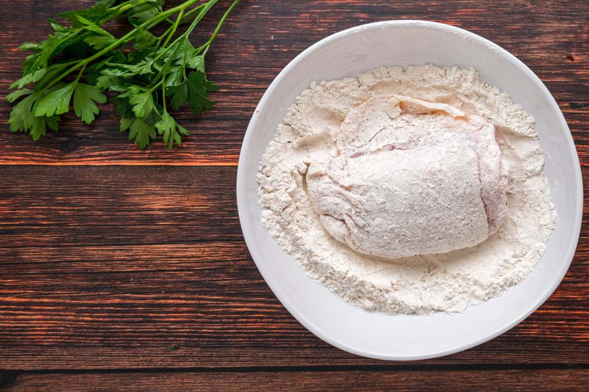 Bowl of mixed seasoned flour on a wood surface.