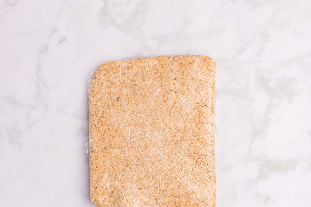Wrapped disc of dough on a marble counter.