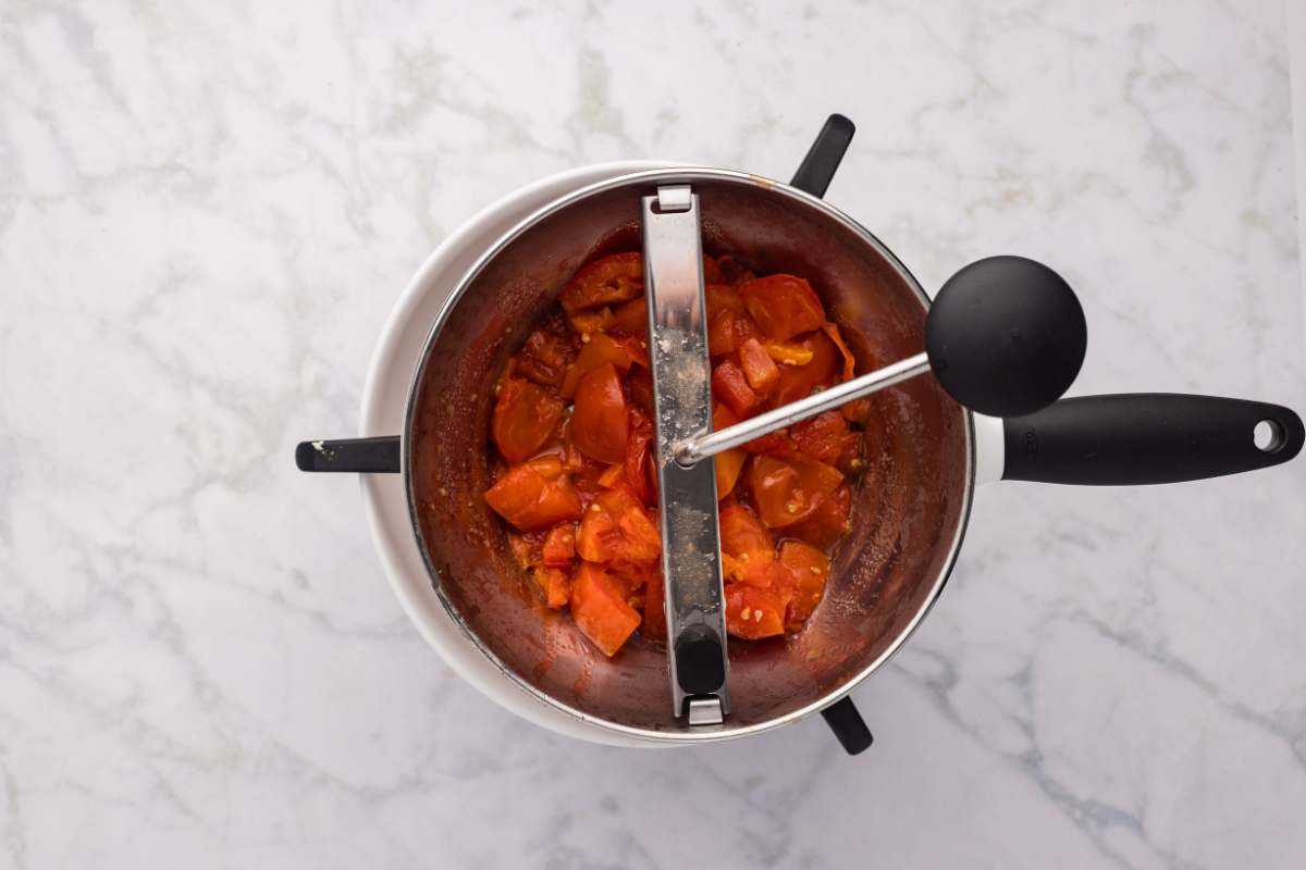 Running cooked tomatoes through a food mill.