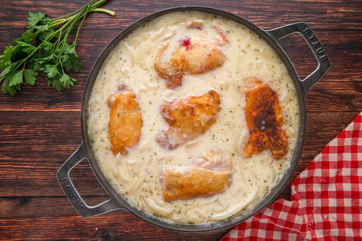 : Chicken thighs in creamy onion gravy before baking.