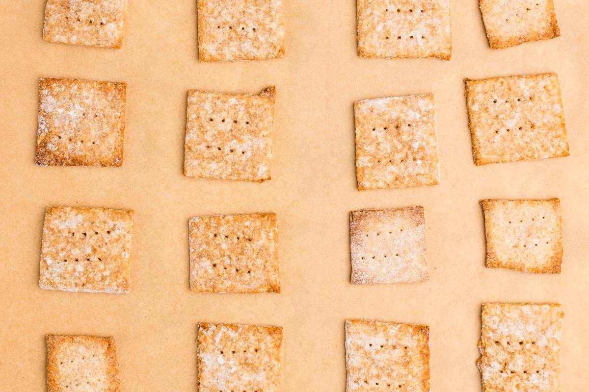 Baked sourdough crackers with golden edges on parchment.