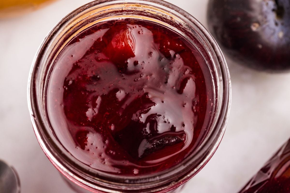 Close-up of finished plum jam inside a glass jar.