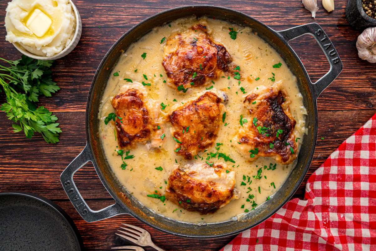 Skillet of smothered chicken garnished with parsley