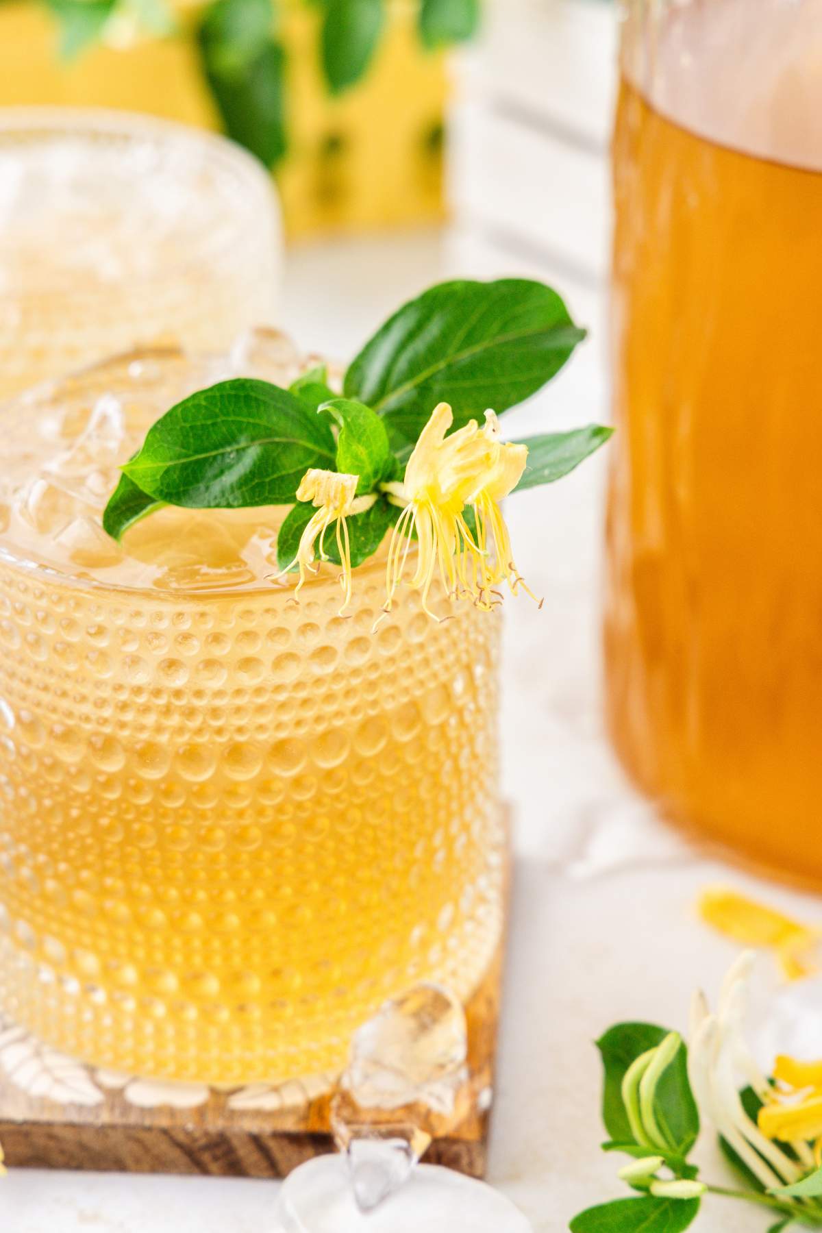Glass of iced honeysuckle tea with flower garnish.