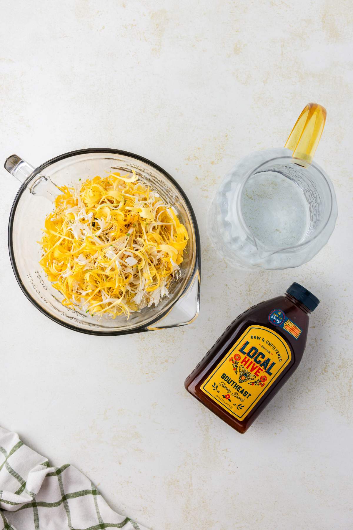 Bowl of honeysuckle flowers next to honey and water pitcher.