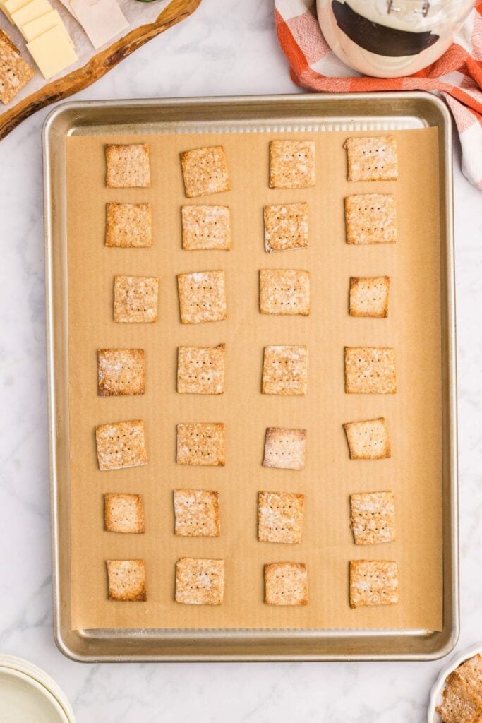 Baked crackers cooling on a parchment-lined baking sheet.