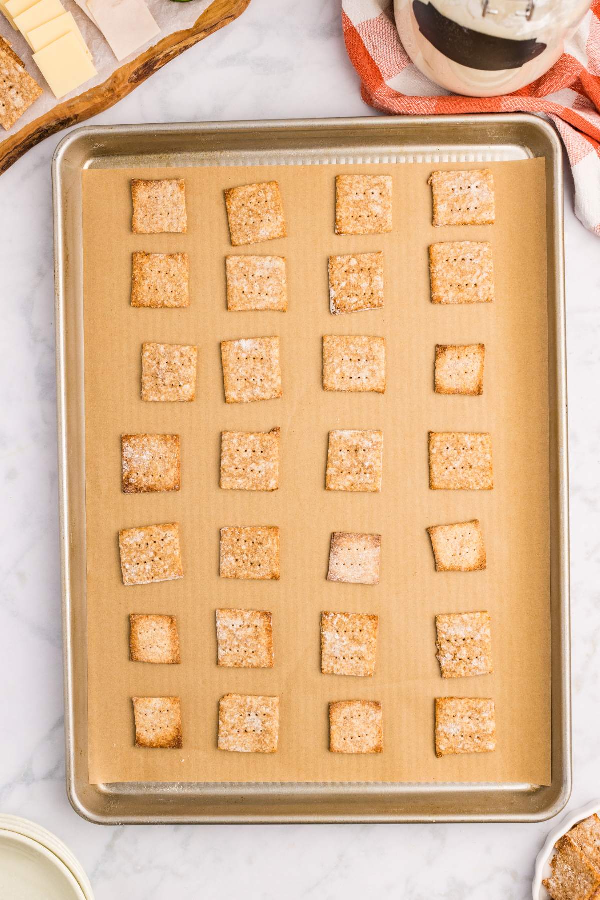 Baked crackers cooling on a parchment-lined baking sheet.