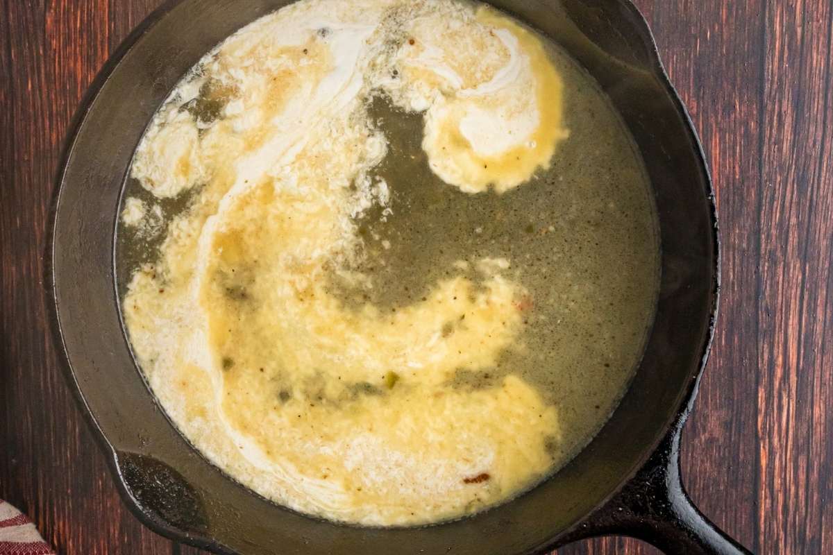 Cream and Parmesan being stirred into a pan sauce.